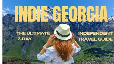 Indie Georgia 7-day independent travel guide blog cover photo featuring a tourist looking at Caucasus mountains.