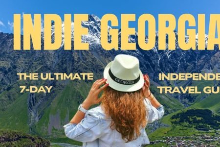 Indie Georgia 7-day independent travel guide blog cover photo featuring a tourist looking at Caucasus mountains.